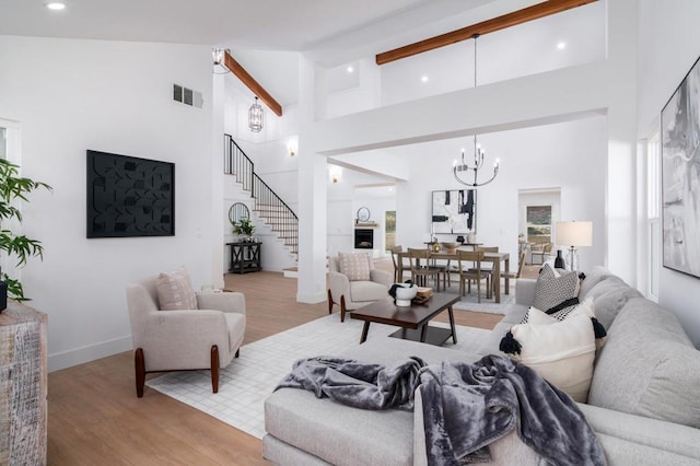 living room with high vaulted ceiling, light hardwood / wood-style floors, and a notable chandelier