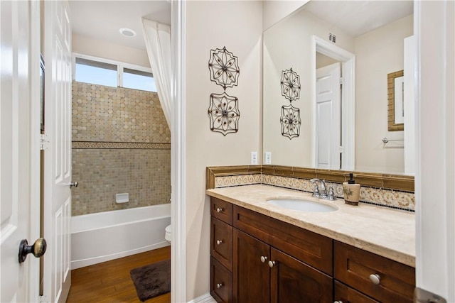 full bathroom with hardwood / wood-style flooring, vanity, toilet, and tiled shower / bath combo