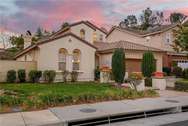 mediterranean / spanish house featuring a garage and a lawn