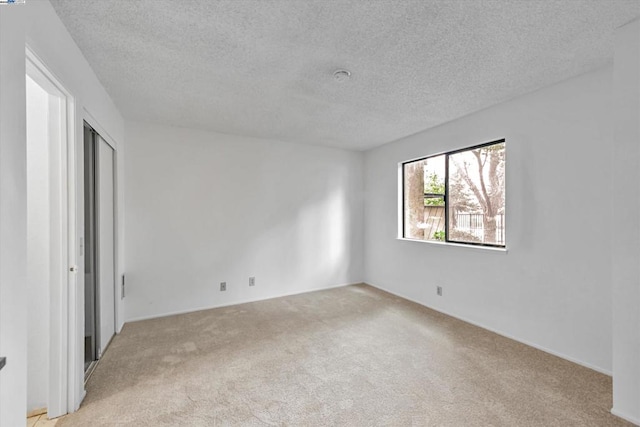 unfurnished bedroom with light colored carpet and a textured ceiling