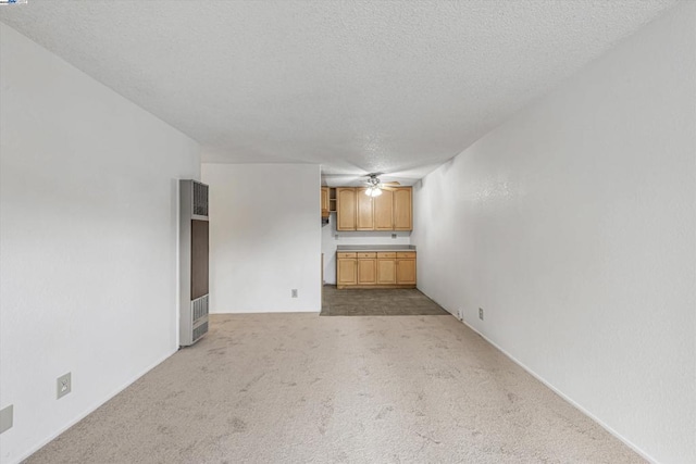 unfurnished living room with light carpet, ceiling fan, and a textured ceiling