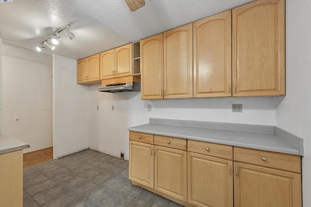 kitchen with ceiling fan, light brown cabinetry, and a textured ceiling