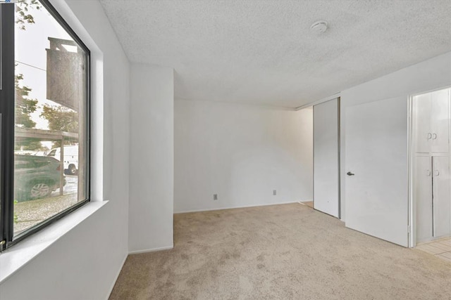 empty room featuring light carpet and a textured ceiling