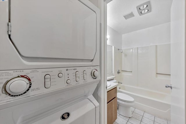 laundry area featuring stacked washing maching and dryer and light tile patterned floors