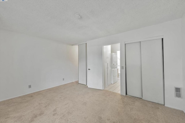 unfurnished bedroom featuring connected bathroom, light colored carpet, and a textured ceiling