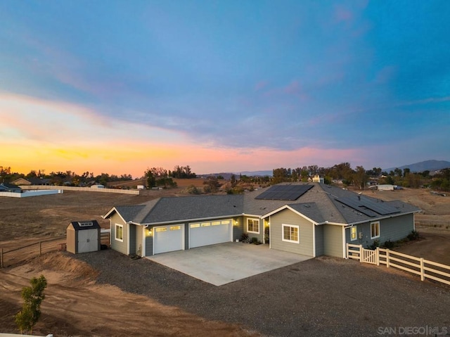 ranch-style house with a garage, solar panels, and a storage unit