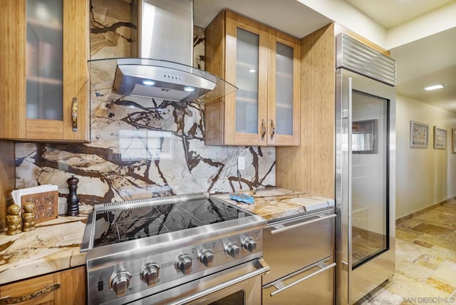 kitchen with high end appliances, light stone counters, decorative backsplash, and island exhaust hood