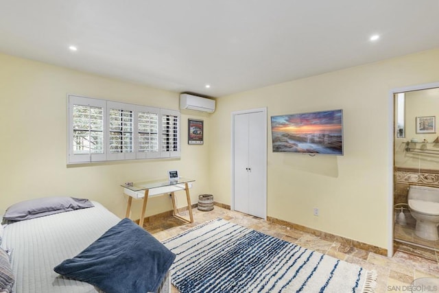 bedroom with ensuite bath and a wall mounted air conditioner