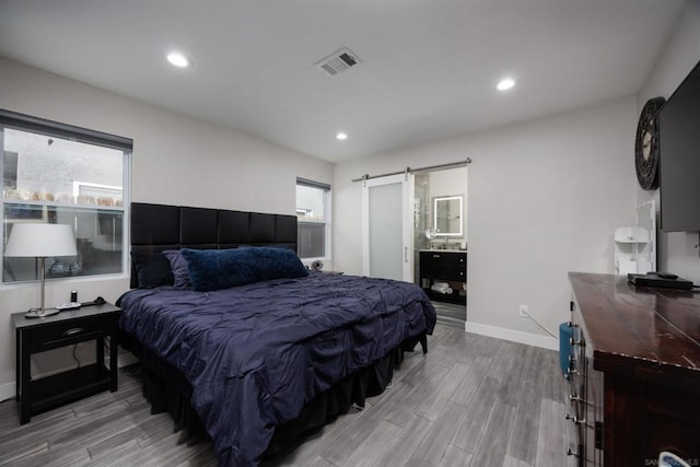 bedroom featuring a barn door and light hardwood / wood-style floors