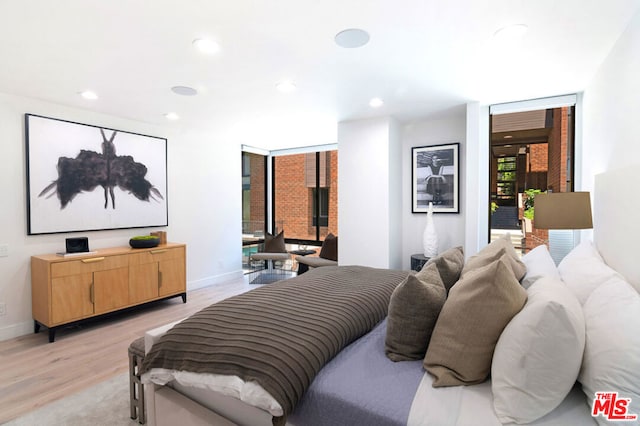 bedroom with floor to ceiling windows and light hardwood / wood-style flooring