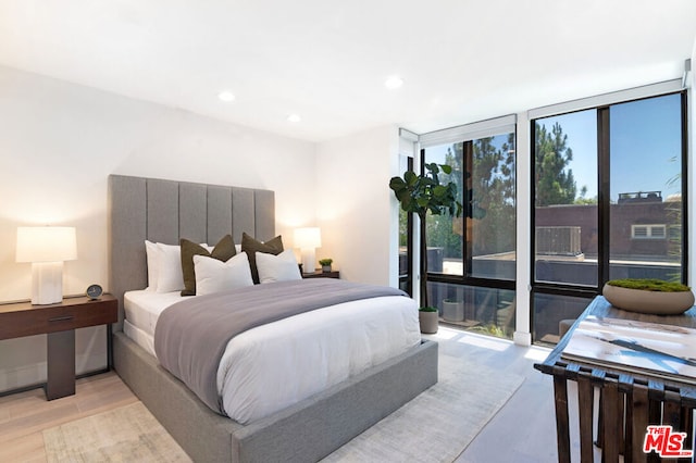 bedroom with floor to ceiling windows and light hardwood / wood-style floors