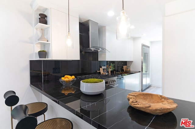 kitchen featuring white cabinetry, white dishwasher, kitchen peninsula, and wall chimney exhaust hood