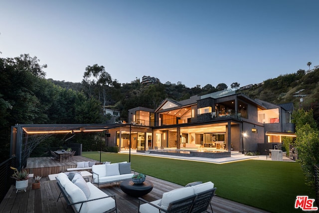 rear view of property featuring a balcony, outdoor lounge area, a pool side deck, and a yard