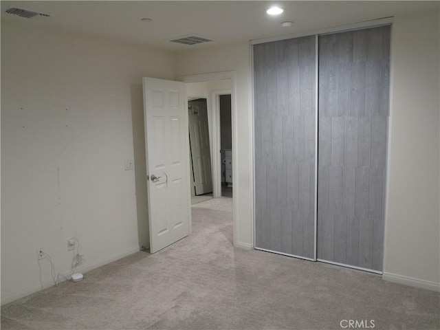 unfurnished bedroom with a closet and light carpet