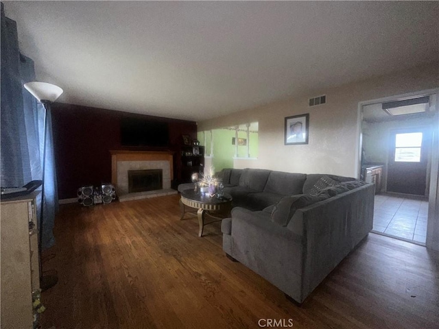 living room with a tile fireplace and dark hardwood / wood-style floors