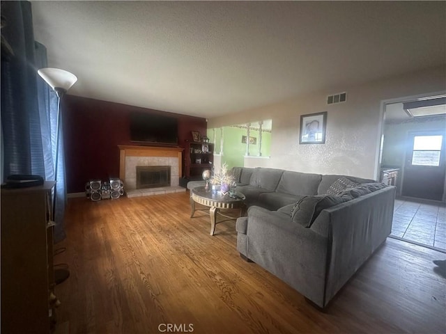 living room featuring a tiled fireplace and hardwood / wood-style floors