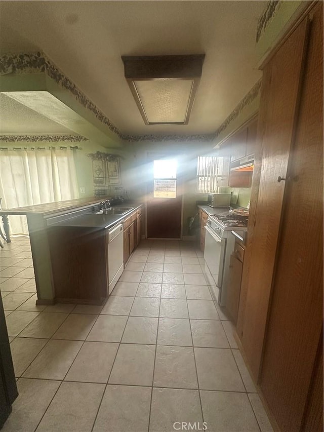 kitchen with sink, light tile patterned floors, and white appliances