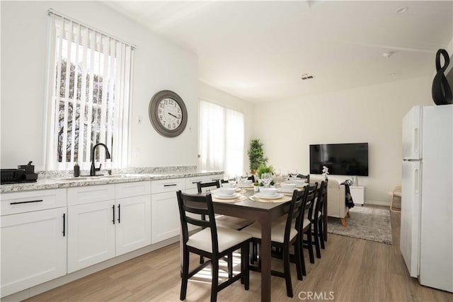 dining space with sink and light hardwood / wood-style floors