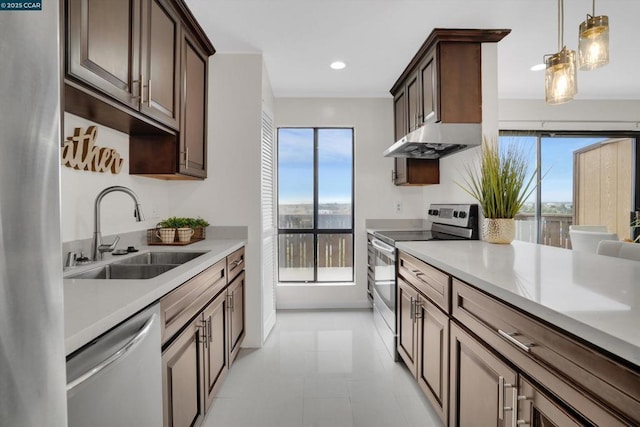 kitchen with sink, a wealth of natural light, stainless steel appliances, and hanging light fixtures