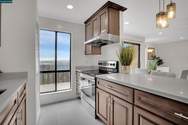 kitchen with light stone counters, pendant lighting, and electric range