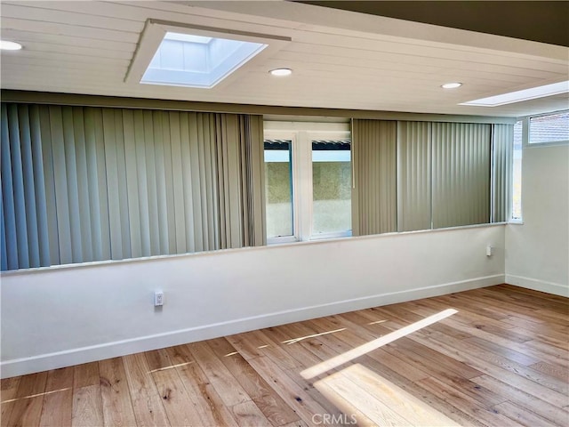 empty room featuring wood-type flooring and a skylight