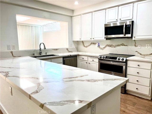 kitchen featuring white cabinetry, stainless steel appliances, light hardwood / wood-style flooring, sink, and light stone counters