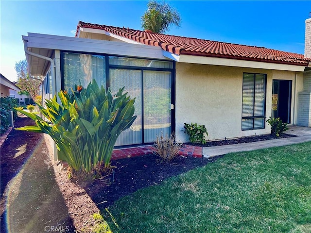 view of side of property with a sunroom and a lawn