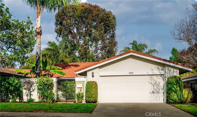 view of front of home with driveway, a tiled roof, and an attached garage