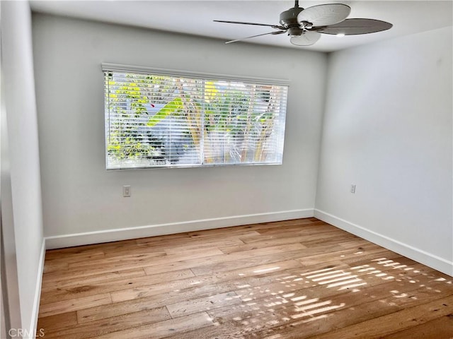 spare room featuring a wealth of natural light, wood-type flooring, and baseboards
