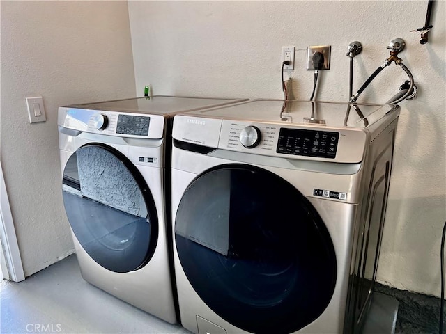 laundry area with laundry area, a textured wall, and washing machine and clothes dryer