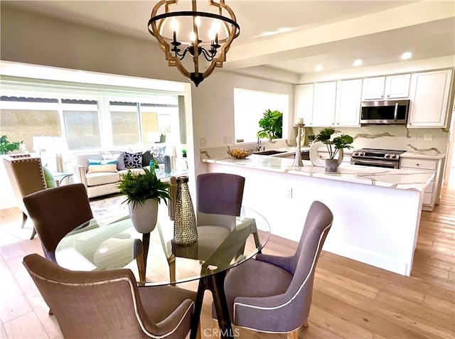 dining space featuring recessed lighting, light wood-style flooring, and a notable chandelier