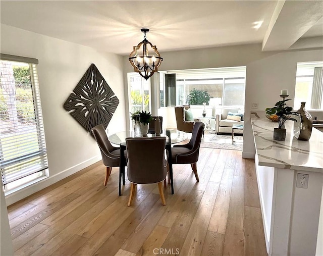 dining area with light wood finished floors, baseboards, and a notable chandelier