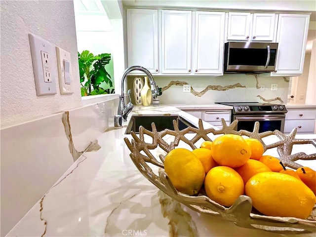 interior details featuring stainless steel appliances, white cabinets, light countertops, and a textured wall