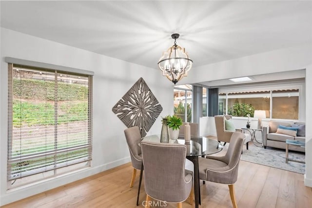 dining space featuring light wood-type flooring, a healthy amount of sunlight, and a notable chandelier