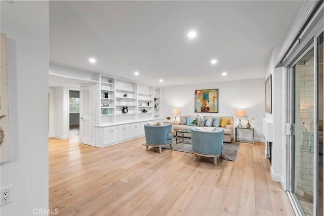 living area featuring light wood-style floors, baseboards, built in features, and recessed lighting