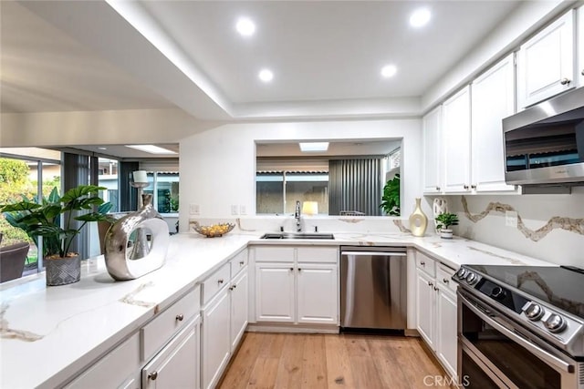kitchen featuring appliances with stainless steel finishes, white cabinets, and a sink