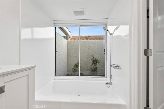 full bathroom with visible vents, vanity, and a washtub