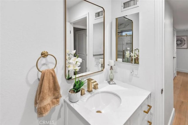 bathroom with baseboards, visible vents, wood finished floors, and vanity