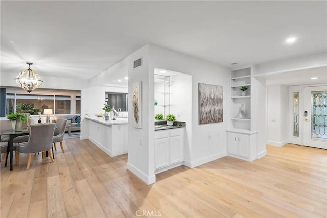 kitchen featuring baseboards, built in features, white cabinets, light wood-style floors, and an inviting chandelier