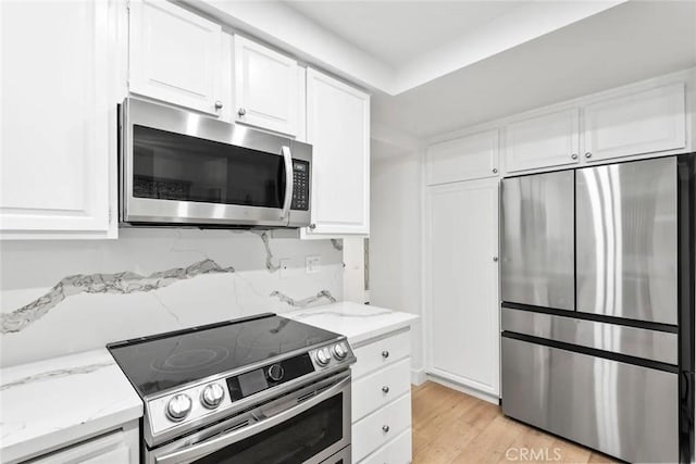kitchen featuring white cabinets, decorative backsplash, light wood-style flooring, appliances with stainless steel finishes, and light stone countertops