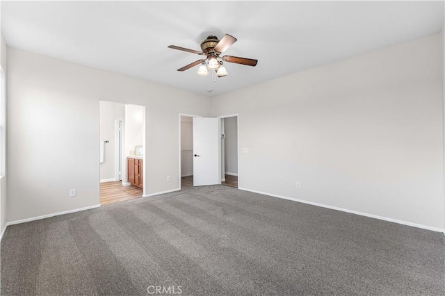 unfurnished bedroom with ensuite bath, ceiling fan, carpet flooring, a spacious closet, and a closet