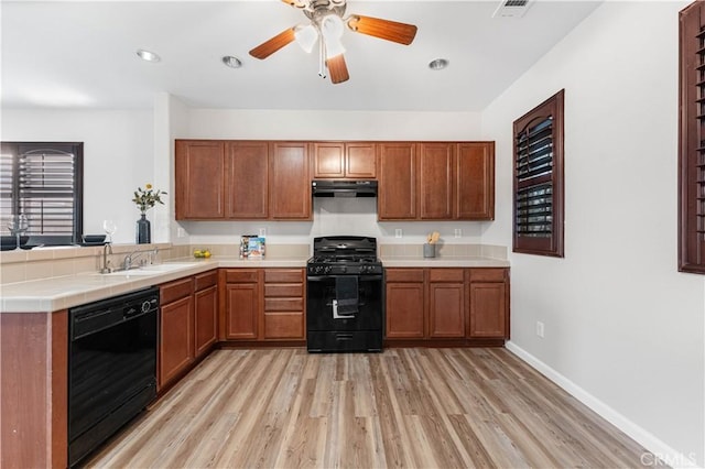 kitchen featuring sink, black appliances, light hardwood / wood-style flooring, ceiling fan, and exhaust hood