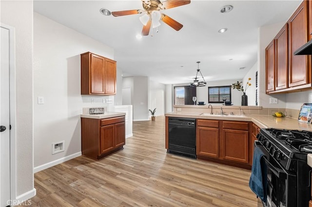 kitchen with black appliances, sink, hanging light fixtures, kitchen peninsula, and light hardwood / wood-style flooring