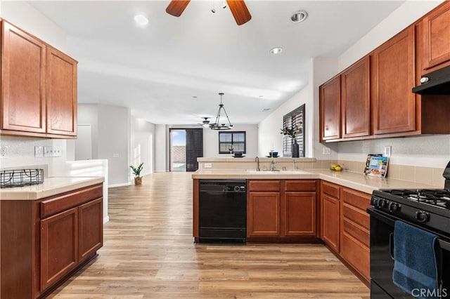 kitchen featuring sink, light hardwood / wood-style flooring, black appliances, decorative light fixtures, and kitchen peninsula