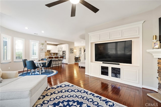 living room with dark hardwood / wood-style flooring and ceiling fan