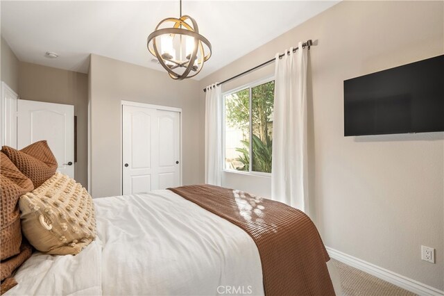 carpeted bedroom with an inviting chandelier and a closet