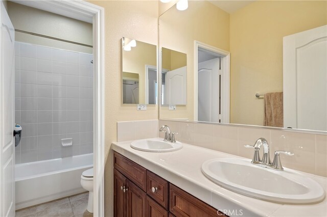 full bathroom featuring tiled shower / bath combo, tasteful backsplash, vanity, tile patterned floors, and toilet