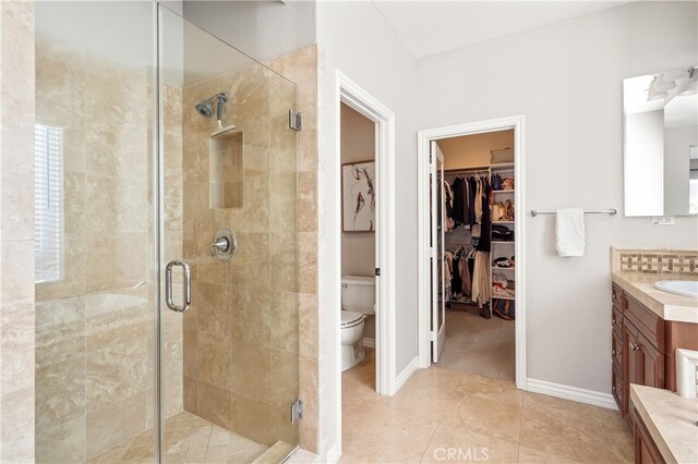 bathroom with tile patterned flooring, vanity, toilet, and a shower with shower door