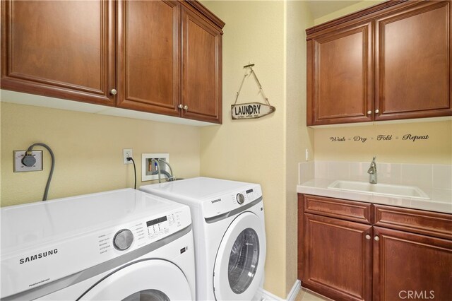 clothes washing area with cabinets, separate washer and dryer, and sink