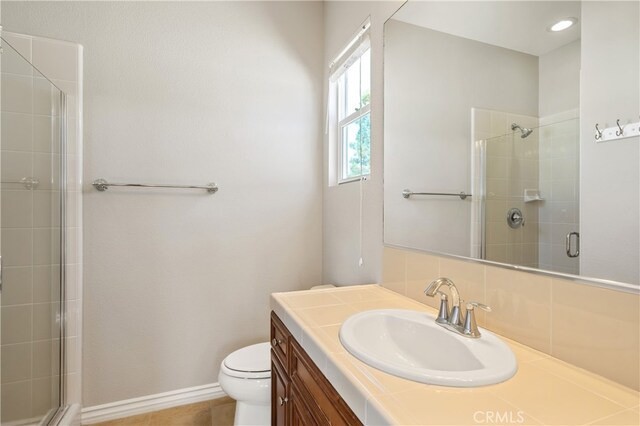 bathroom featuring vanity, a shower with shower door, and toilet